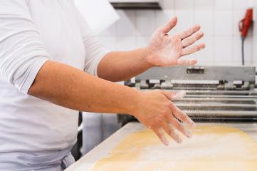 baker's hands dust flour over rolled-out dough, creating a cloud of fine particles. The scene captures the preparation process in a professional baking environment : Stock Photo or Stock Video Download rcfotostock photos, images and assets rcfotostock | RC Photo Stock.: