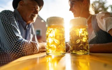 Bavarian Beer mugsl on table with senior man and woman in the background at beer garden or Oktoberfest, Munich, Germany- Stock Photo or Stock Video of rcfotostock | RC Photo Stock