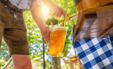 Bavarian man in leather trousers is pouring a large lager beer in tap from wooden beer barrel in the beer garden. Background for Oktoberfest or Wiesn, folk or beer festival- Stock Photo or Stock Video of rcfotostock | RC Photo Stock