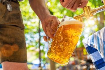 Bavarian man in leather trousers is pouring a large lager beer in tap from wooden beer barrel in the beer garden. Background for Oktoberfest or Wiesn, folk or beer festival (German for: O’zapft is!) - Stock Photo or Stock Video of rcfotostock | RC Photo Stock