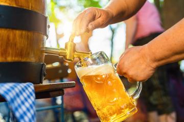 Bavarian Waitress in Tracht, Dirndl  is pouring a large lager beer in tap from wooden beer barrel in the beer garden. Background for Oktoberfest, folk or beer festival (German for: O’zapft is!) - Stock Photo or Stock Video of rcfotostock | RC Photo Stock