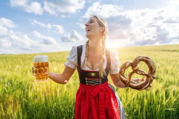 Bavarian woman in traditional German tracht outfit, holding a beer and pretzel in a sunny field celebrating Oktoberfest or dult festival in munich.- Stock Photo or Stock Video of rcfotostock | RC Photo Stock