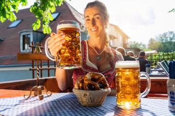 Bavarian woman with beer and pretzel in beautiful Beer garden or oktoberfest at a sunny day- Stock Photo or Stock Video of rcfotostock | RC Photo Stock