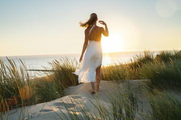 beautiful woman walks barefoot through sand dunes towards to sea at sunset- Stock Photo or Stock Video of rcfotostock | RC Photo Stock