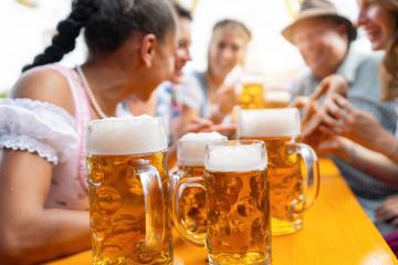 Beer Mugs on a table in a beer tent with lively friends enjoying beers and food at oktoberfest or dult- Stock Photo or Stock Video of rcfotostock | RC Photo Stock