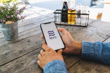 BERLIN, GERMANY JULY 2019: Woman hand holding iphone Xs with logo of Libra in a Restaurant. Libra Facebook cryptocurrency and bitcoin cryptocurrency smartphone share, Libra coins concept.- Stock Photo or Stock Video of rcfotostock | RC-Photo-Stock