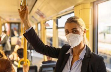 Business woman wearing surgical FFP2 protective holding on to a handle in a public transportation- Stock Photo or Stock Video of rcfotostock | RC Photo Stock
