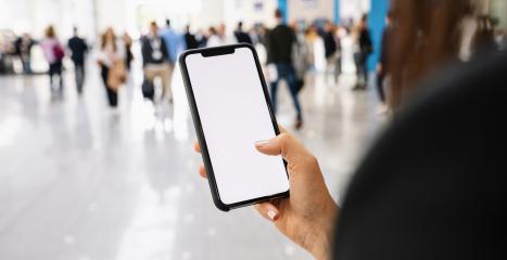 Businesswoman hand holding black cellphone with white screen at a trade fair, copyspace for your individual text.- Stock Photo or Stock Video of rcfotostock | RC Photo Stock