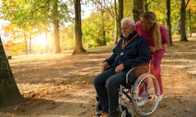 Cheerful elderly man in a wheelchair with a nurse in a park, wearing a SOS button, autumn setting- Stock Photo or Stock Video of rcfotostock | RC Photo Stock
