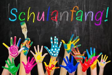 Children’s colorful painted hands raised in excitement against a chalkboard background with the word 