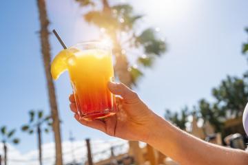 Close-up of a hand holding a colorful tropical cocktail with a backdrop of sunlit palm trees at caribbean island hotel  : Stock Photo or Stock Video Download rcfotostock photos, images and assets rcfotostock | RC Photo Stock.: