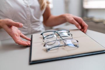 Close-up of a saleswoman's hands presenting a selection of eyeglasses on a display tray in a optical store.- Stock Photo or Stock Video of rcfotostock | RC Photo Stock