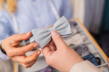 Close-up of hands holding a light blue patterned bow tie in a tailor shop- Stock Photo or Stock Video of rcfotostock | RC Photo Stock