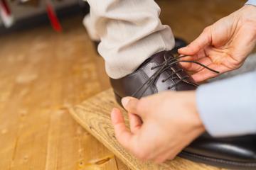 Close-up of hands tying the laces of a new brown leather shoe on a wooden board at a wedding store : Stock Photo or Stock Video Download rcfotostock photos, images and assets rcfotostock | RC Photo Stock.: