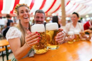 close-up of two friends holding large beer mugs, toasting and smiling in celebration at Oktoberfest or dult, with pretzels and a lively atmosphere under the red and white striped tent : Stock Photo or Stock Video Download rcfotostock photos, images and assets rcfotostock | RC Photo Stock.: