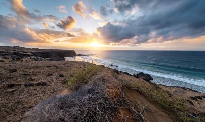 Coastal landscape at sunset with rocky shoreline and waves, under a dramatic sky at Playa de Cofete, Fuerteventura, Canary Islands.- Stock Photo or Stock Video of rcfotostock | RC Photo Stock