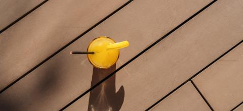 cocktail with orange garnish on a sunny wooden deck, creating a long shadow at a caribbean island hotel- Stock Photo or Stock Video of rcfotostock | RC Photo Stock