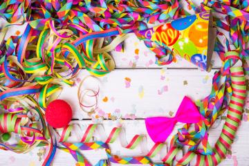 Colorful party decorations including streamers, confetti, a party hat, a red clown nose, and a bright pink bow on a white wooden table, creating a festive and vibrant celebration scene : Stock Photo or Stock Video Download rcfotostock photos, images and assets rcfotostock | RC Photo Stock.: