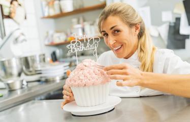 confectioner smiling proudly and decorating big Birthday cake muffin at pastry bakery : Stock Photo or Stock Video Download rcfotostock photos, images and assets rcfotostock | RC Photo Stock.: