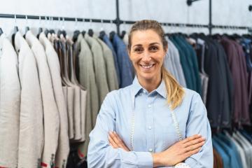 Confident tailor with arms crossed standing in front of suit jackets on hangers : Stock Photo or Stock Video Download rcfotostock photos, images and assets rcfotostock | RC Photo Stock.: