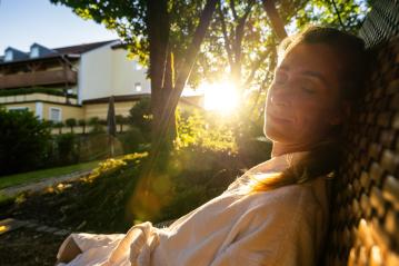 Content woman relaxing on a swing in the sunlight, eyes closed at a spa resort- Stock Photo or Stock Video of rcfotostock | RC Photo Stock