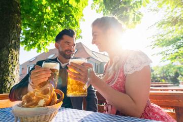 Couple in Bavarian Tracht sitting in Beer garden or oktoberfest and enjoying a glass of beer and the sun- Stock Photo or Stock Video of rcfotostock | RC Photo Stock