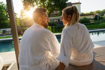 Couple in love looking to each other white bathrobes enjoying sunset by a pool in a spa wellness hotel- Stock Photo or Stock Video of rcfotostock | RC Photo Stock