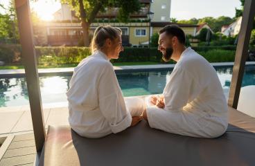 Couple in white bathrobes enjoying sunset by sitting by a pool in a spa wellness hotel- Stock Photo or Stock Video of rcfotostock | RC Photo Stock