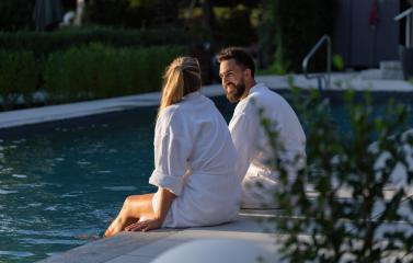 Couple in white robes sitting back to back at the edge of a pool in a spa hotel- Stock Photo or Stock Video of rcfotostock | RC Photo Stock