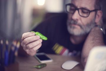 Creative designer looks at green pepper, hot chili pepper- Stock Photo or Stock Video of rcfotostock | RC Photo Stock