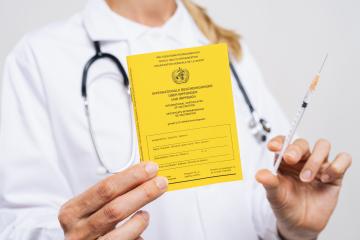 Doctor showing an international certificate of the vaccination with syringe for corona virus covid 19 vaccination shot- Stock Photo or Stock Video of rcfotostock | RC Photo Stock