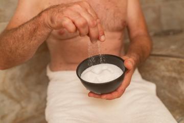 Elderly Man holds a bowl of salt in his hand at the steam bath or hammam to exfoliate the skin for body massage in a spa or wellness resort - Stock Photo or Stock Video of rcfotostock | RC Photo Stock