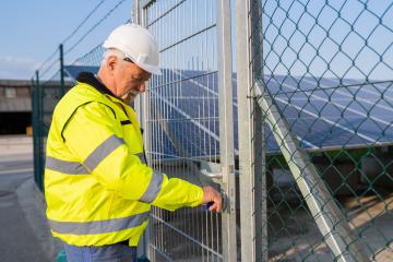 Electrical engineer in safety gear opening a gate to a solar field : Stock Photo or Stock Video Download rcfotostock photos, images and assets rcfotostock | RC Photo Stock.: