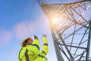 Electrical female engineer talking in a walkie talkie and pointing to control a high voltage electricity pylon. Close-up Electrical power lines and towers with bright sun- Stock Photo or Stock Video of rcfotostock | RC Photo Stock