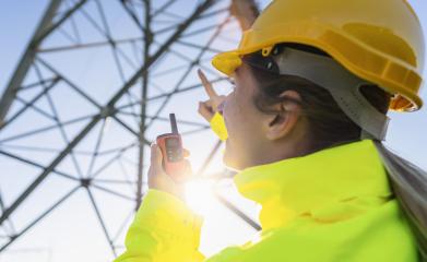 Electrical female engineer using walkie talkie to control a high voltage electricity pylon. Electrical power lines and towers with bright sun- Stock Photo or Stock Video of rcfotostock | RC Photo Stock