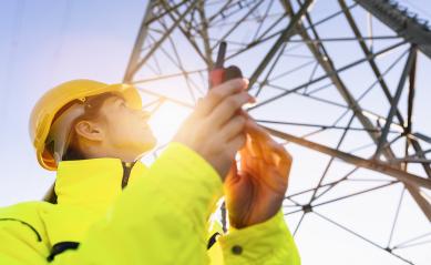 Electrical female engineer watching up and uses a walkie talkie to control a high voltage electricity pylon. Electrical power lines and towers with bright sun : Stock Photo or Stock Video Download rcfotostock photos, images and assets rcfotostock | RC Photo Stock.: