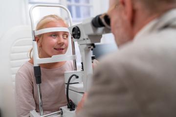 Eye examination with young girl looking into an optometry machine at eye clinic- Stock Photo or Stock Video of rcfotostock | RC Photo Stock