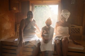 Family in a finnish sauna laughing together, man on left, woman with towel on head on right, child in middle at wellness hotel- Stock Photo or Stock Video of rcfotostock | RC Photo Stock