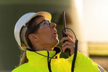 female engineer talking skeptical in a walkie talkie to checking wind turbine system at windfarm - Stock Photo or Stock Video of rcfotostock | RC Photo Stock