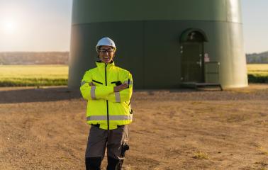 female engineer with safety jacket standing in front of a wind turbine at a new energy farm. regenerative energy concept image- Stock Photo or Stock Video of rcfotostock | RC Photo Stock