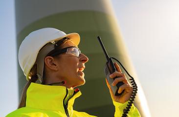 female engineer with safety jacket using walkie talkie to checking wind turbine system at windfarm - Stock Photo or Stock Video of rcfotostock | RC Photo Stock