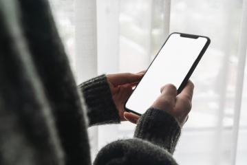 Female hand holding black cellphone with white screen at home against a window, copyspace for your individual text.- Stock Photo or Stock Video of rcfotostock | RC-Photo-Stock