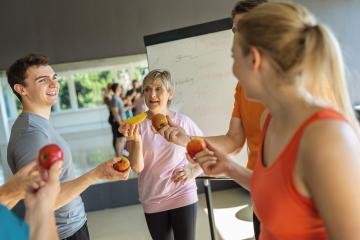 Fitness group discussing nutrition holding fruits with a whiteboard in the background- Stock Photo or Stock Video of rcfotostock | RC Photo Stock