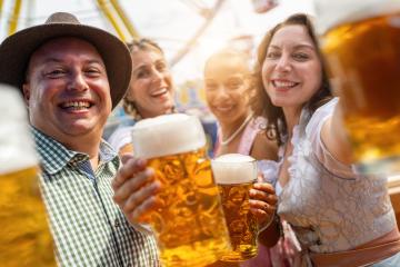 Four friends happily toasting with beer mugs at an outdoor fairground with amusement rides in the background at a vibrant Oktoberfest or dult in germany : Stock Photo or Stock Video Download rcfotostock photos, images and assets rcfotostock | RC Photo Stock.: