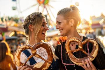 girlfriends look at each other  holding pretzel or brezen on a Bavarian fair or oktoberfest or duld in national costume or Dirndl in germany  : Stock Photo or Stock Video Download rcfotostock photos, images and assets rcfotostock | RC Photo Stock.: