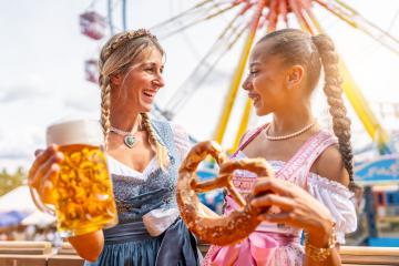 girlfriends look to each other with pretzel or brezen and beer mug on a Bavarian fair or oktoberfest or duld in national costume or Dirndl- Stock Photo or Stock Video of rcfotostock | RC Photo Stock