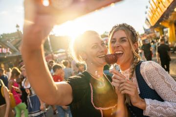 Girlfriends making selfie wearing dirndl and holding candy apples at a Bavarian fair or oktoberfest or duld in national costume or Dirndl : Stock Photo or Stock Video Download rcfotostock photos, images and assets rcfotostock | RC Photo Stock.: