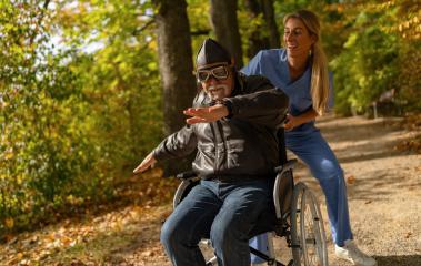 grandpa in aviator attire and goggles mimics flying, pushed by a laughing nurse in an autumn park. nursery home concept image  : Stock Photo or Stock Video Download rcfotostock photos, images and assets rcfotostock | RC Photo Stock.: