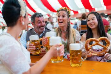 group of friends at Oktoberfest tent joyfully cheers with frothy beer mugs, holding a large pretzel. They are wearing traditional outfits and celebrating in a lively atmosphere in munich : Stock Photo or Stock Video Download rcfotostock photos, images and assets rcfotostock | RC Photo Stock.: