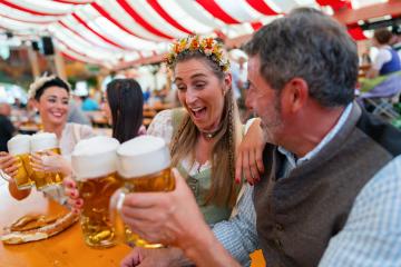 group of friends excitedly toasting with large beer mugs, celebrating at Oktoberfest or dult, with pretzels and a lively red and white striped tent in the background in munich : Stock Photo or Stock Video Download rcfotostock photos, images and assets rcfotostock | RC Photo Stock.: